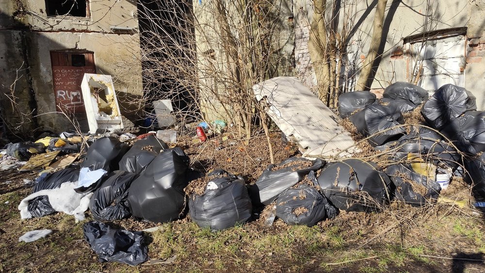 Śmieci leżące przy opuszczonych budynkach